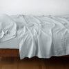 Linen Fitted Sheet | Cloud | fitted sheet with matching rumpled flat sheet and sleeping pillow - side view.