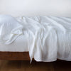 Linen Fitted Sheet | White | fitted sheet with matching rumpled flat sheet and sleeping pillow - side view.