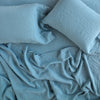 Linen Twin Flat Sheet | Linen flat sheet in cenote, rumpled over a matching fitted sheet and sleeping pillows - overhead view.