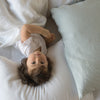 Linen Pillowcase (Single) | A young toddler laying on a linen pillowcase and looking at the camera - overhead view.