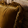 Close-up of Loulah sham ruffle detail - showcasing the 4 inch silkvelvet ruffle with raw-edge eyelash detail - shone in honeycomb against a distressed wood headboard.