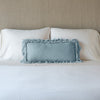 Loulah Throw Pillow | Cloud | pillow on a white bed - cropped end of bed view.