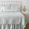 Luna Twin Coverlet | Cloud | coverlet on a shining, monochromatic bed with matching shams - end of bed view.