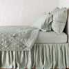 Luna Coverlet | Eucalyptus | coverlet neatly folded back to reveal linen reverse, on a monochromatic bed - side view.
