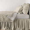 Luna Coverlet | Fog | coverlet neatly folded back to reveal linen reverse, on a monochromatic bed - side view.