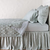 Luna coverlet neatly folded back to reveal linen reverse, on a monochromatic bed - eucalyptus, side view.