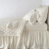 Luna Coverlet | Parchment | coverlet neatly folded back to reveal linen reverse, on a monochromatic bed - side view.