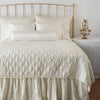 Luna Twin Coverlet | Parchment | coverlet on a shining, monochromatic bed with matching shams - end of bed view.