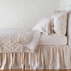Luna Twin Coverlet | Pearl | coverlet neatly folded back to reveal linen reverse, on a monochromatic bed - side view.