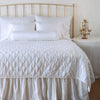 Luna Coverlet | White | coverlet on a shining, monochromatic bed with matching shams - end of bed view.