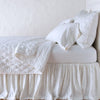 Luna Sham | White | shams with a matching coverlet pulled back over monochromatic sheeting - side view.
