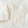 Lynette Blanket | Winter White | Close up of blanket, with a corner turned back to showcase the linen back - overhead view.