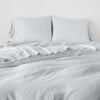 Madera Luxe Duvet Cover | Cloud | duvet cover with matching sleeping pillows and sheeting against a white wall - end of bed view.