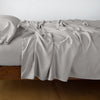 Madera Luxe Fitted Sheet | Fog | fitted sheet with matching rumpled flat sheet and sleeping pillow - side view.