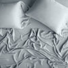 Madera Luxe Fitted Sheet | Mineral | rumpled sheeting and sleeping pillows - overhead view.