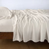 Madera Luxe Fitted Sheet | Parchment | fitted sheet with matching rumpled flat sheet and sleeping pillow - side view.