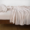 Madera Luxe Fitted Sheet | Pearl | fitted sheet with matching rumpled flat sheet and sleeping pillow - side view.