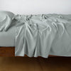 Madera Luxe Flat Sheet | Eucalyptus | Rumpled flat sheet with matching fitted sheet and sleeping pillow - side view.
