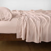 Madera Luxe Flat Sheet | Rouge | Rumpled flat sheet with matching fitted sheet and sleeping pillow - side view.