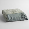 Mirabella Baby Blanket — Limited Release | Mineral | a silk and tencel™ jacquard baby blanket folded and shot against a white background with the ruffled trim situated to be visible