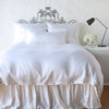 Paloma Duvet Cover | White | duvet cover with matching pillows and bed skirt - end of bed view.