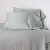 Paloma Pillowcase (Single) | Mineral | Paloma sleeping pillows leaning upright against a white wall on monochromatic sheeting - mineral, cropped three-quarter angle.