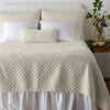 Silk Velvet Quilted Twin Coverlet | Parchment | coverlet and matching shams on a neatly made, white bed - end of bed view.