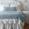 Silk Velvet Quilted Throw Pillow | Cloud | 16x36 pillow and matching throw blanket on a white, neatly made bed - end of bed view.