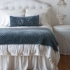 Silk Velvet Quilted Blanket | Mineral | throw blanket and matching lumbar pillow on a neatly made white bed - end of bed view.