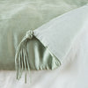 Taline Blanket | Eucalyptus | Close up of blanket, with a corner turned back to showcase the midweight linen back and corner tassel - overhead view.