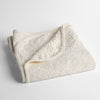 Vienna Baby Blanket | Winter White | a folded cotton chenille baby blanket trimmed in silk velvet shot overhead at a slight angle against a white background.
