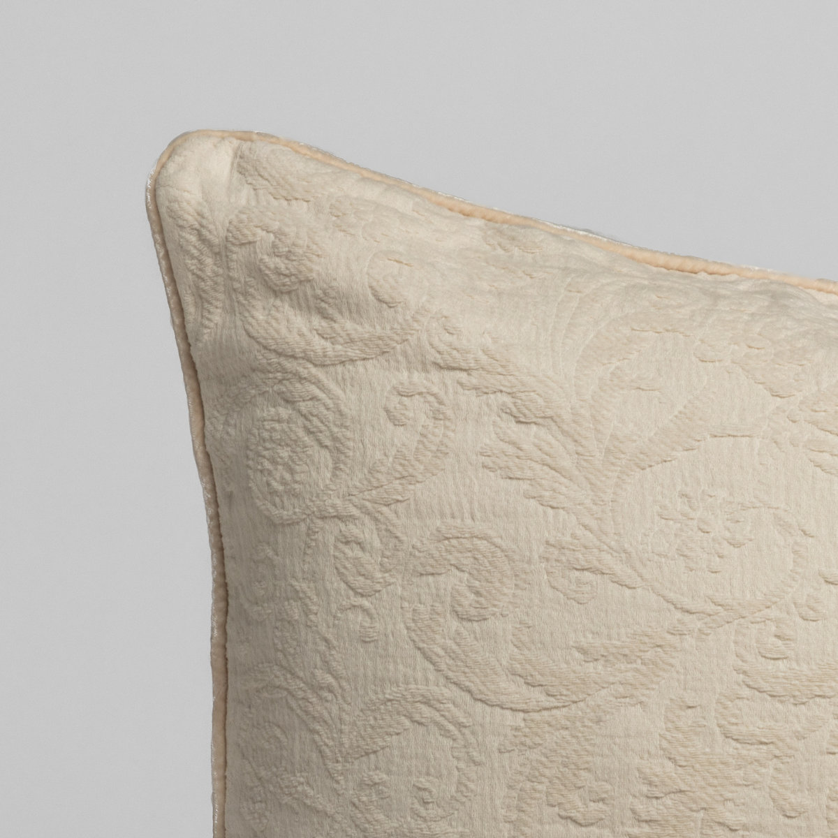 Adele Throw Pillow | Natural | a close up of the corner of a textured damask pillow in natural, a warm neutral.