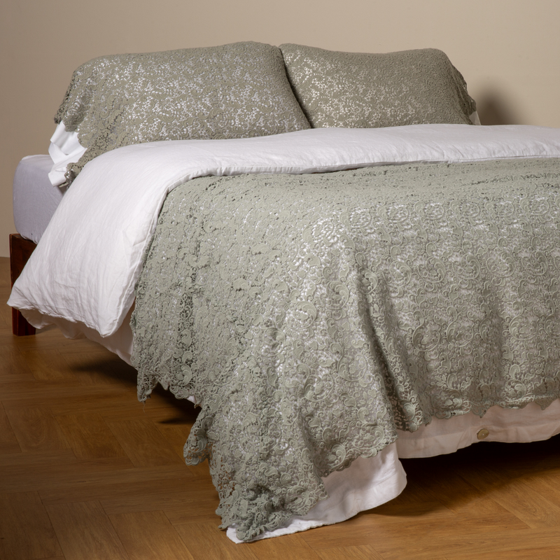 Allora Bed Scarf | Eucalyptus | cotton lace bed scarf draped across the foot of a bed dressed in linen sheets and duvet cover in winter white -  shown with matching lace pillowcase covers over a linen liner in winter white.
