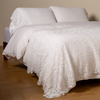 Allora Bed Scarf | White | cotton lace bed scarf draped across the foot of a bed dressed in linen sheets and duvet cover in winter white -  shown with matching lace pillowcase covers over a linen liner in winter white.