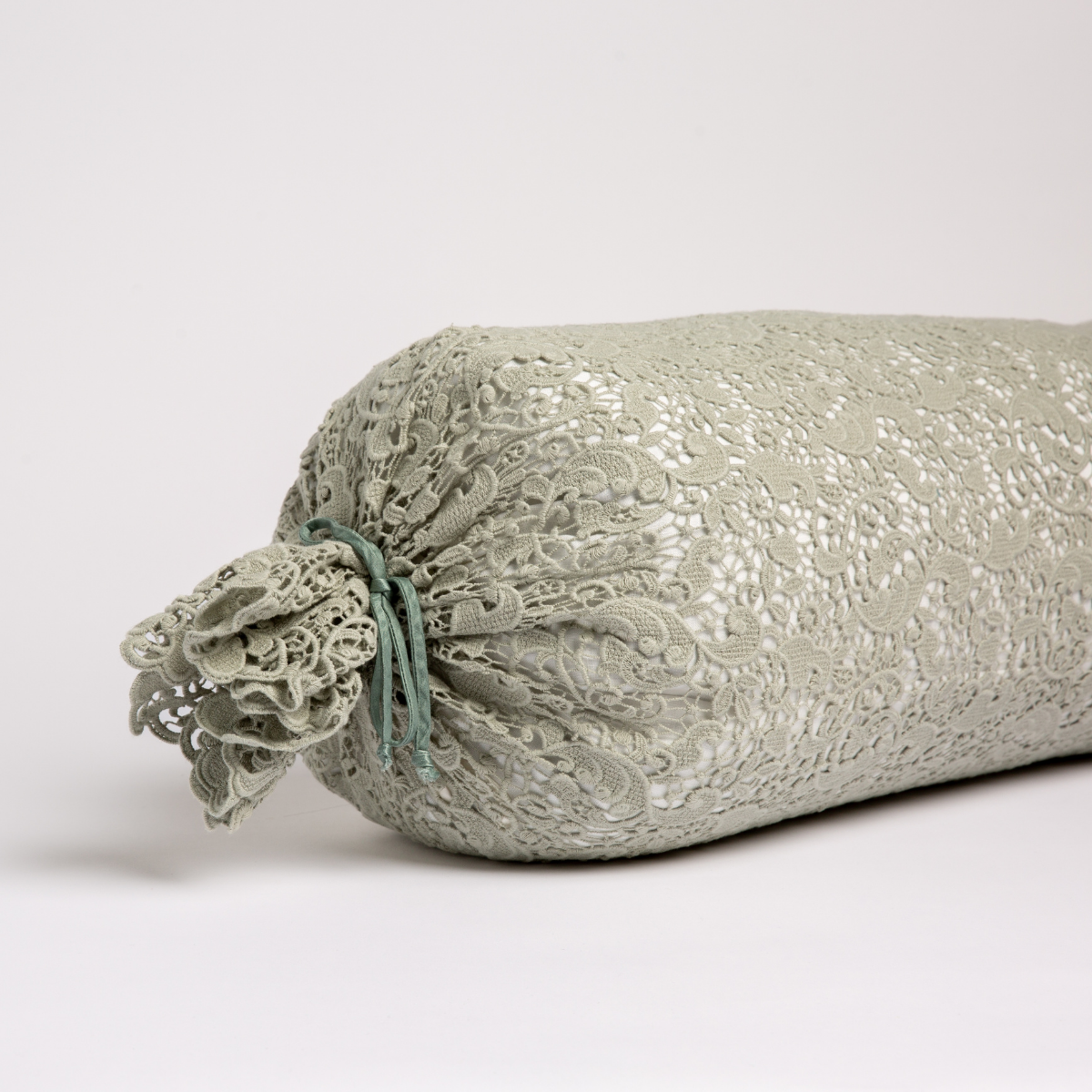 Allora Lace Throw Pillow | Eucalyptus | one end of a lace boslter cover on a winter white liner against a white background.