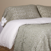 Allora Lace Pillowcase (Single) | Eucalyptus | a pair of cotton lace pillowcase covers on winter white liners shown on a bed dressed in winter white linen with a matching cotton lace bed scarf.