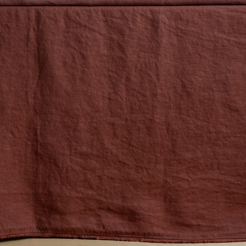 Autumn | A close-up side view of a bed with the Austin bed skirt in Autumn, a rich terracotta tone.