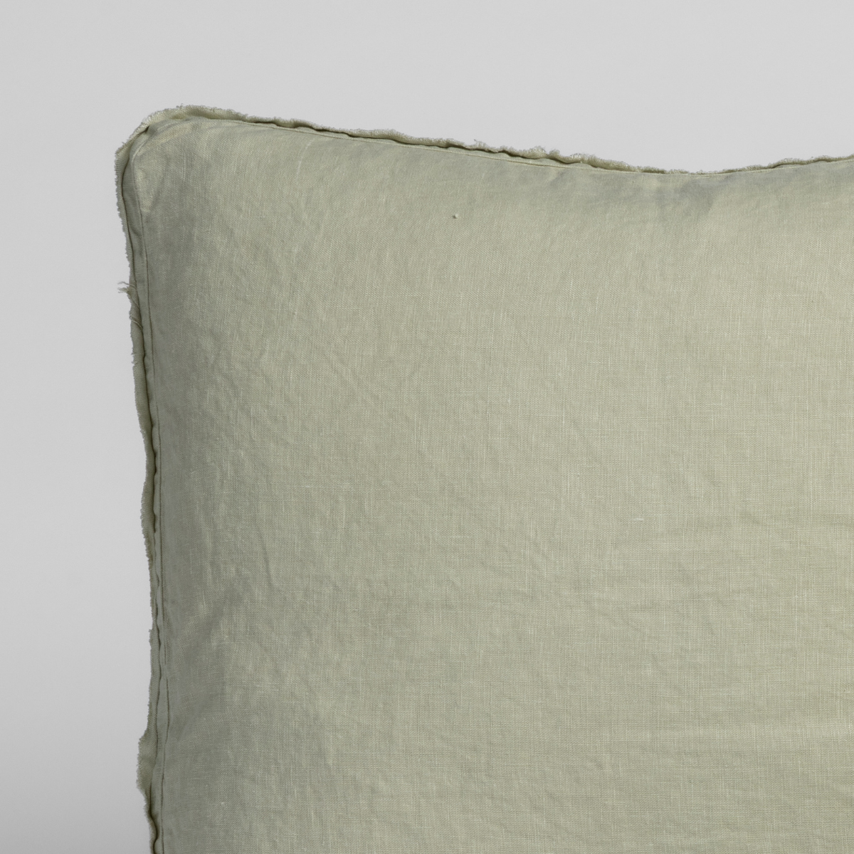 Austin Sham | Desert Sage | close up of a pillow corner in desert sage, a serenely elegant green, offering a hushed hue, shown against a plain background.