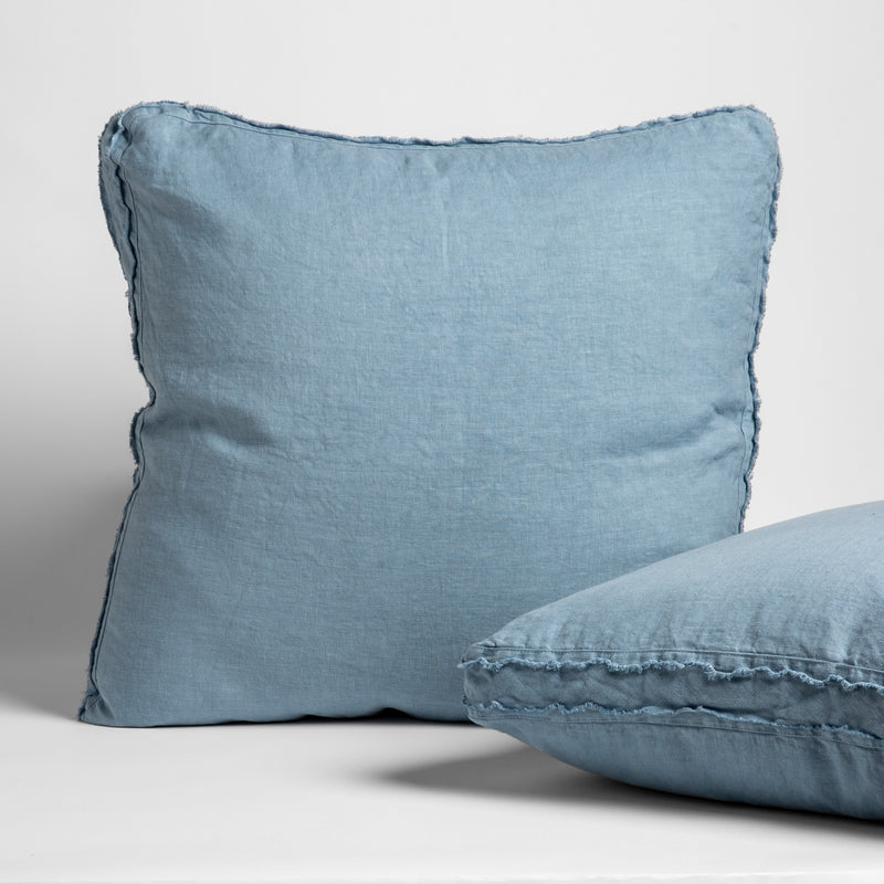 Austin Throw Pillow | Tahoe Blue | two midweight linen pillows, one propped up, one laying, with raw edged corners trimming their gusset on a white background.