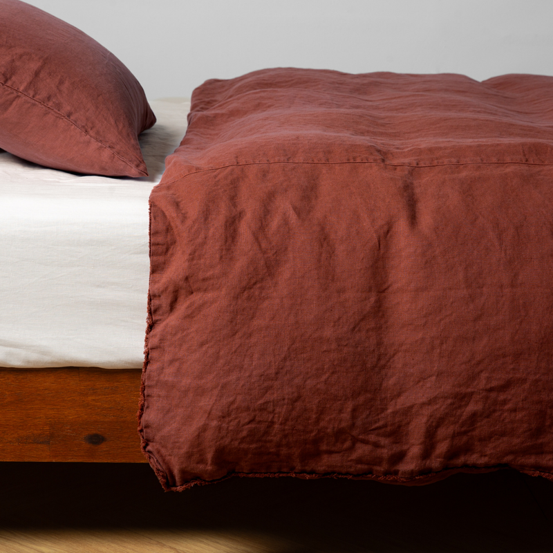 Autumn | A close-up side view of a bed with our Austin Duvet Cover and a matching pillowcase in Autumn, a rich terracotta tone.