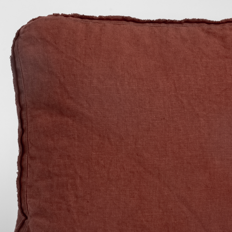 Autumn | A close-up of the corner of an Austin Throw Pillow in Autumn, a rich terracotta tone, shown against a white background.