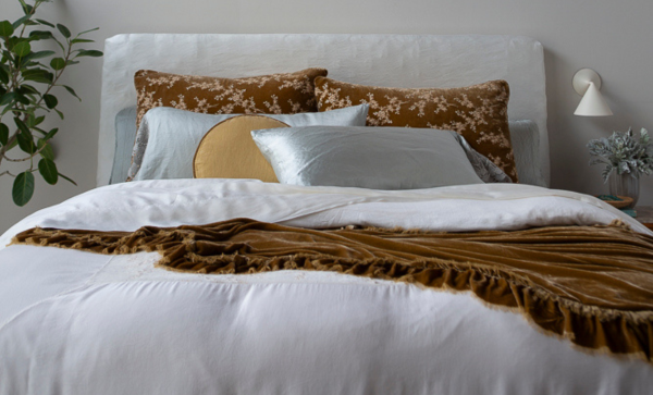 Second Honeymoon: A Bella Notte Linens bed featuring Lynette Luxe Shams in Honeycomb and Paloma Pillowcases in Cloud atop a Lynette Luxe Duvet Cover in Winter White and a Honeycomb Loulah blanket dresses the end of the bed