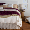 Allora Lace Throw Pillow | a 3/4 shot of a bed dressed in neutral tones with pops of color - a lace bolster with a contrasting liner is shown in at the head of the bed.