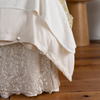 Allora Bed Skirt | a close up of the cotton lace bed skirt layered with a linen bedskirt and tencel duvet cover.