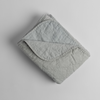 Austin Blanket - Holiday Release | Cloud | a quilted midweight linen blanket folded  with a corner folded back - shot overhead against a white background.