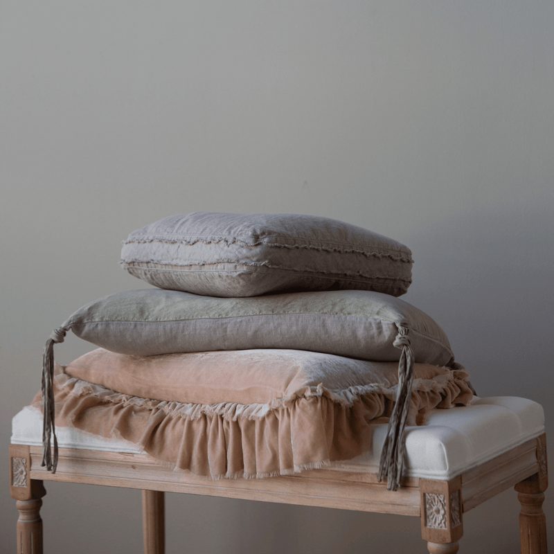 Austin Throw Pillow | throw pillows in various colors scattered on an antique stool.