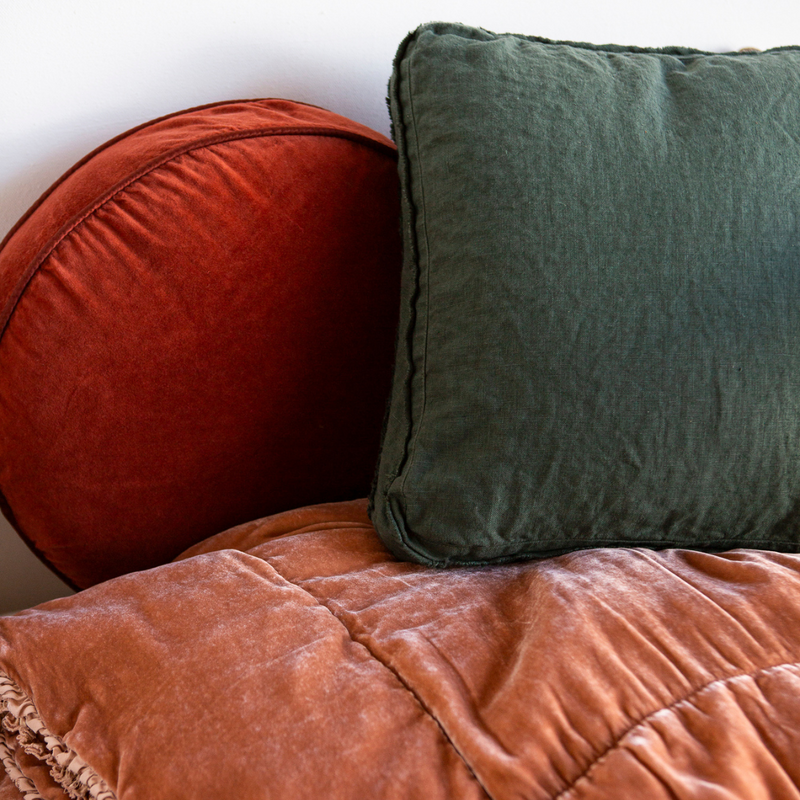 Austin Throw Pillow | A colorful cluster of living pieces shown in orangish tones with a dark green throw pillow.