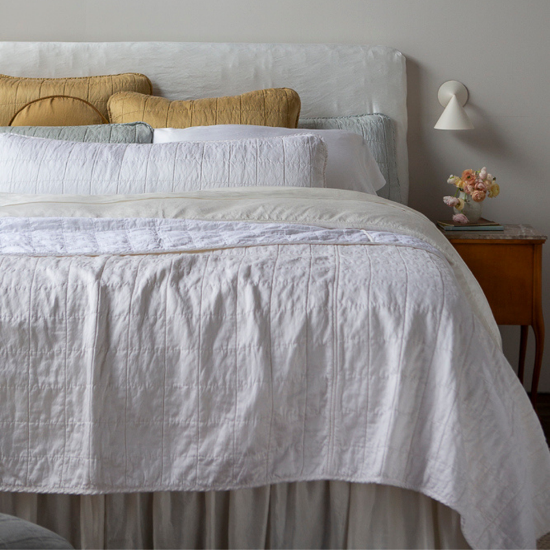Sel Coverlet | a quilted charmeuse coverlet layered over a duvet cover and sheets - shown from the foot of the bed with the coverlet folded back shows the cotton sateen back and how it takes the dye differently than its front.