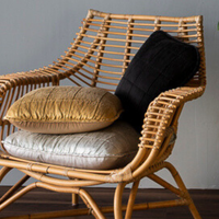 A wooden chair with three Sel throw pillows on top. Two 18x18 pillows in Corvino and Honeycomb, and one 24x24 in Cloud.