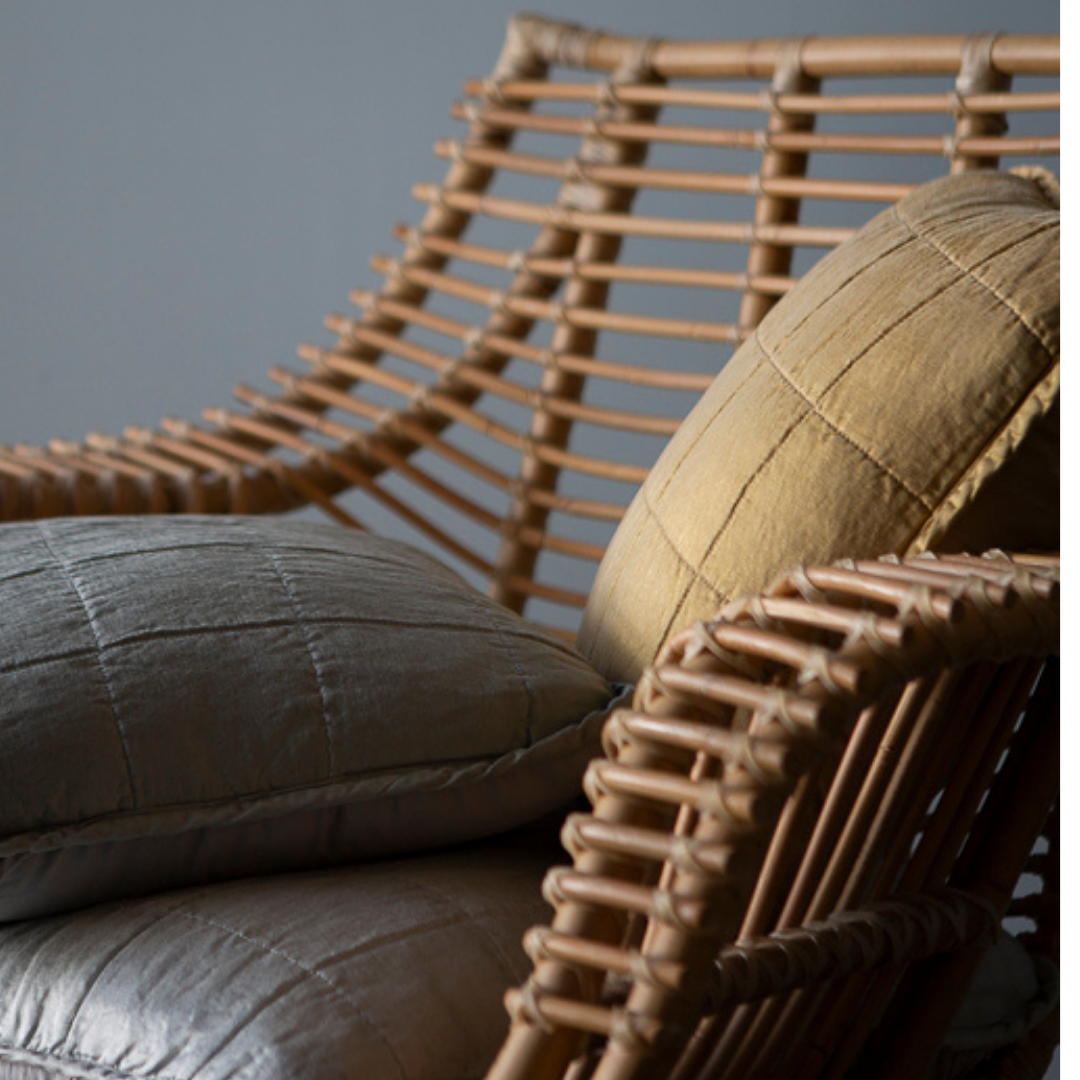 Sel Throw Pillow | a close up of quilted charmeuse throw pillows in a rattan chair.